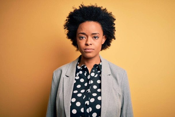Young beautiful African American afro businesswoman with curly hair wearing jacket with serious expression on face. Simple and natural looking at the camera. - Photo, Image