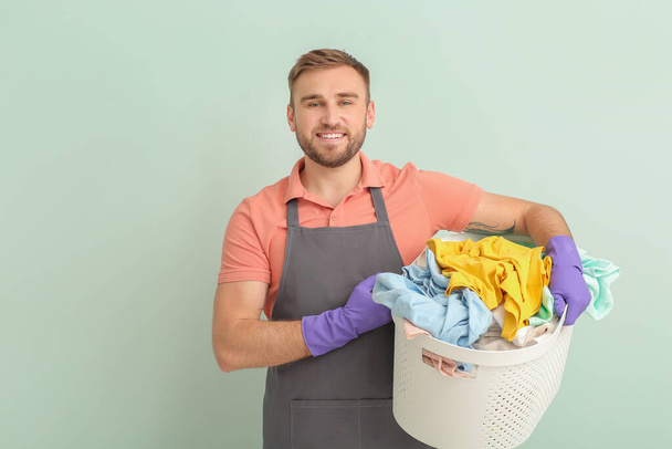 Young man with laundry on grey background - Photo, Image