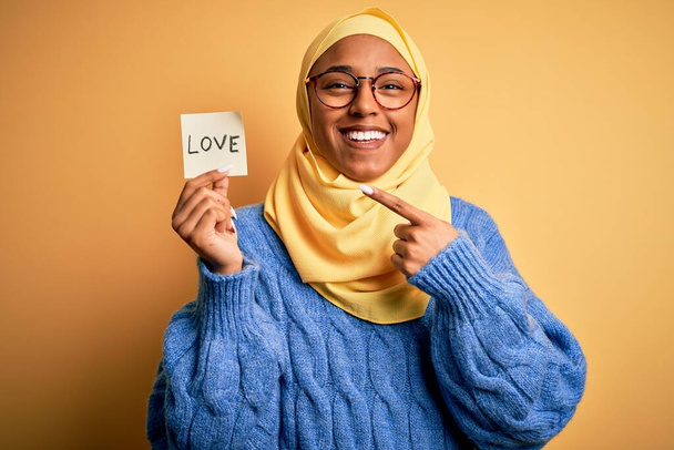 若いですアフリカ系アメリカ人女性身に着けていますムスリムヒジャーブ保持愛リマインダー紙メッセージ非常に幸せなポインティングとともに手と指 - 写真・画像