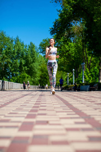 Young beautiful girl jogging along the promenade in the hot summer - Photo, image