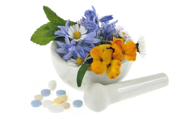 Mörser und Stößel mit Minzblättern, Blüten und Medizin in Nahaufnahme auf weißem Hintergrund - Foto, Bild