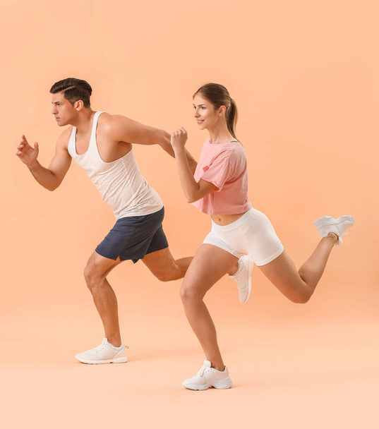 Sporty running young couple on color background - Valokuva, kuva