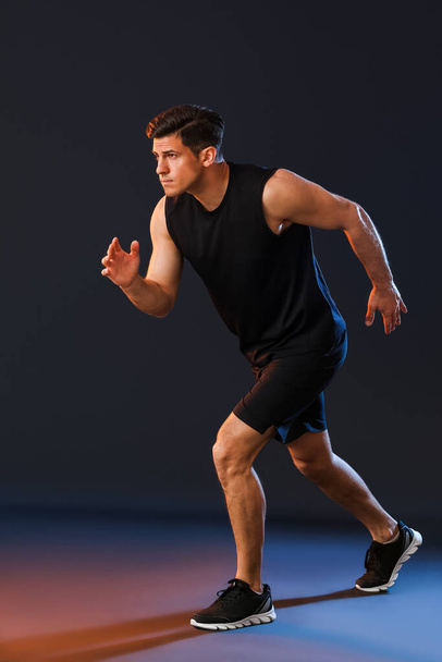 Sporty young male runner on dark background - Foto, imagen