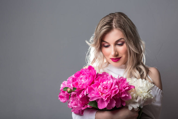 Краса весни без алергії. дівчина насолоджується квітучими рожевими півоніями квітами. Насолоджуйтесь весною без місця алергії для тексту
. - Фото, зображення