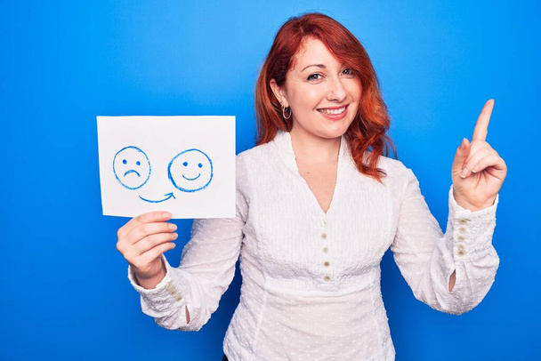 Redhead trenér žena žádající o depresi držení papíru s emoce změna zpráva s úsměvem šťastný ukazující rukou a prstem na stranu - Fotografie, Obrázek