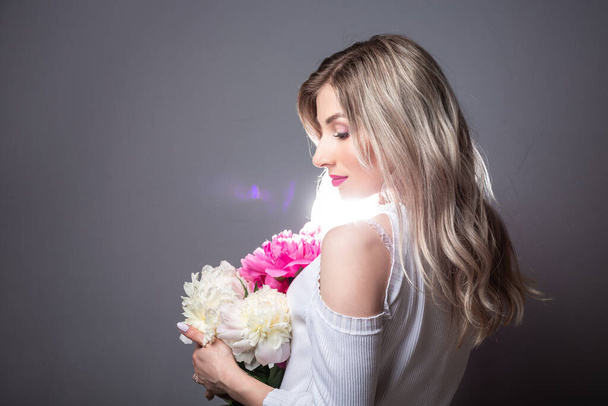 Young pretty woman with pink peonies. Spring allergy concept. space for text. - Foto, Imagem