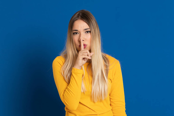 Blonde girl wearing a yellow T-shirt on a blue background - Foto, immagini