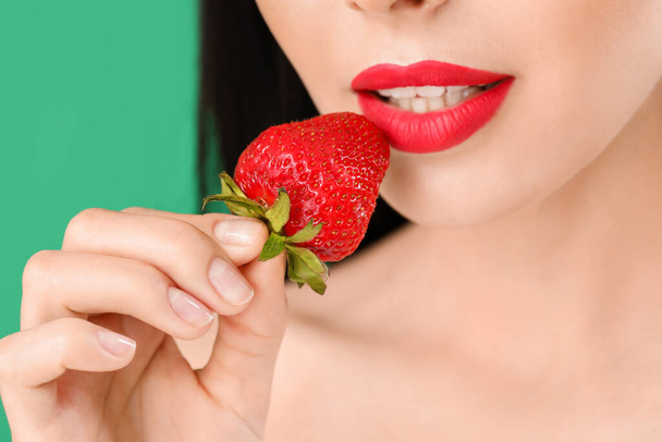 Sexy young woman with strawberry on color background, closeup - Фото, изображение