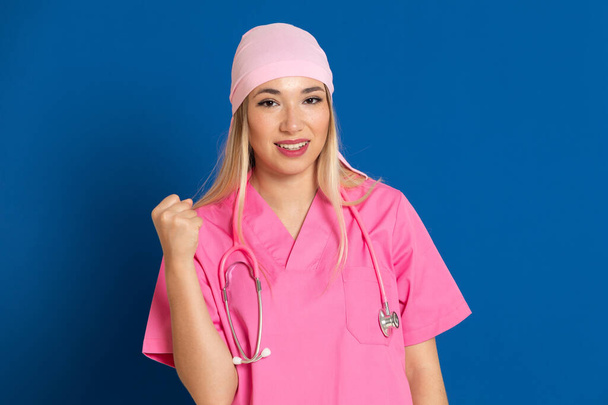 Jeune médecin avec un uniforme rose et une écharpe sur fond bleu
 - Photo, image