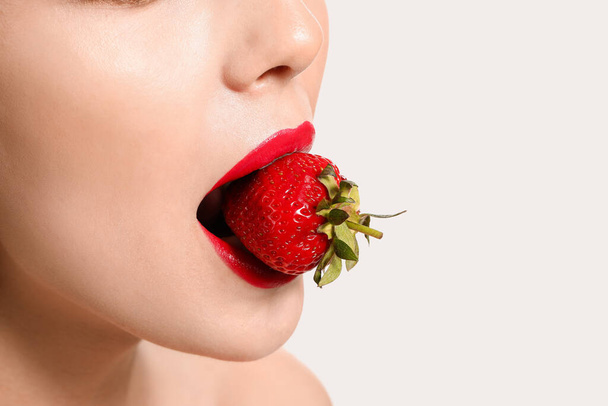 Sexy young woman with strawberry on white background, closeup - Foto, imagen