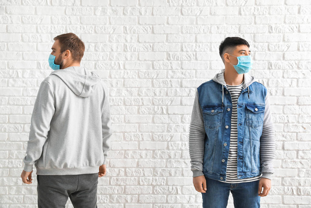 Young men wearing protective masks on white background. Concept of epidemic - Photo, Image