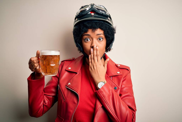 Nuori afroamerikkalainen afro-moottoripyöräilijä nainen, jolla on kiharat hiukset juomapurkki olutta kansi suu käsin järkyttynyt häpeästä erehdyksestä, pelon ilmauksesta, pelästyneenä hiljaisuudessa, salainen käsite - Valokuva, kuva