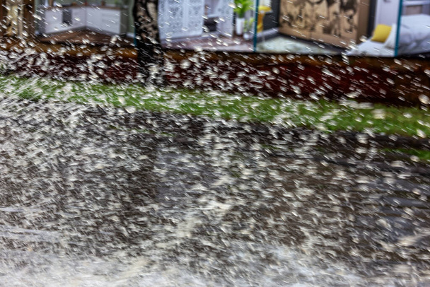 на затопленной дороге во время наводнения, вызванного проливными дождями. Машины плавают по воде, наводняя улицы. Всплеск на машину. Затопленная городская дорога с большой лужей. Наводнение после сильных дождей в городе
 - Фото, изображение