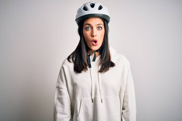 Young cyclist woman with blue eyes wearing bike helmet over isolated white background afraid and shocked with surprise expression, fear and excited face. - Fotografie, Obrázek