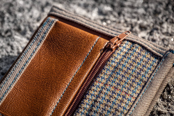 El yapımı kahverengi deri cüzdanlı fermuarlı bozuk para cebi ve taş zemin üzerinde damalı tekstil. Erkek aksesuar. - Fotoğraf, Görsel
