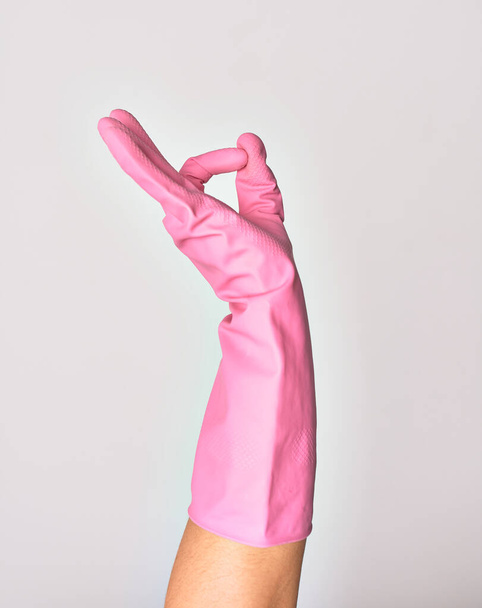 Mano de mujer joven caucásica con guante de limpieza rosa haciendo signo ok sobre fondo blanco aislado - Foto, Imagen