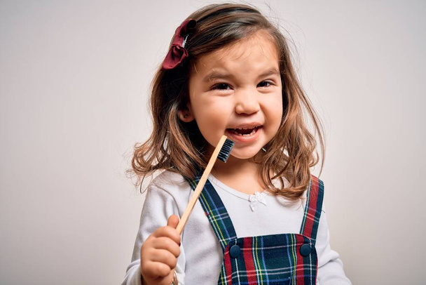 Pequeña niña pequeña cepillándose los dientes usando cepillo de dientes y pasta oral, limpiando los dientes y la lengua como rutina saludable de atención médica matutina. Aprender educación dental
 - Foto, imagen