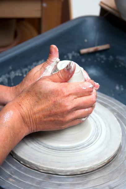 Eine Keramikkünstlerin bei der Arbeit in ihrem heimischen Töpferatelier und wirft eine Schale auf ein Rad - Foto, Bild