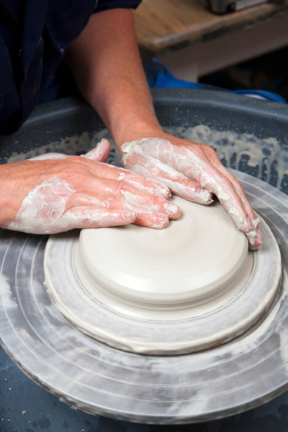 Artystka ceramiki pracująca w pracowni garncarskiej, rzucająca miskę na koło. Otwarcie. - Zdjęcie, obraz