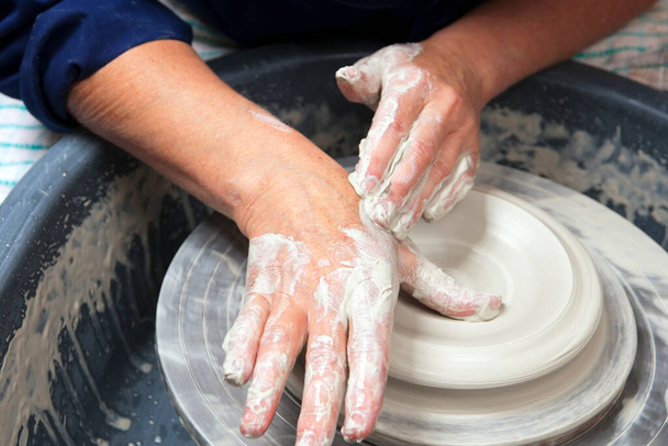 Eine Keramikkünstlerin bei der Arbeit in ihrem heimischen Töpferatelier und wirft eine Schale auf ein Rad. Öffnung. - Foto, Bild