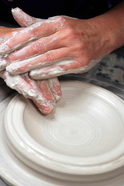 Una artista de cerámica en el trabajo en su casa estudio de cerámica, lanzando un tazón en una rueda. Apertura
. - Foto, Imagen