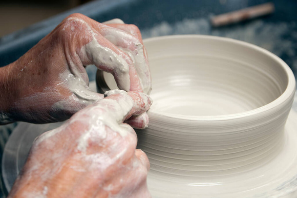 Eine Keramikkünstlerin bei der Arbeit in ihrem heimischen Töpferatelier und wirft eine Schale auf ein Rad - Foto, Bild