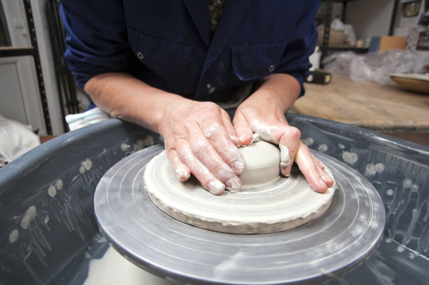 A lady ceramics artist at work in her home pottery studio, centering for a mug - Photo, Image