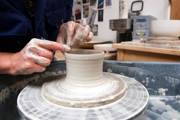 A lady ceramics artist at work in her home pottery studio, forming a mug shape - Photo, Image