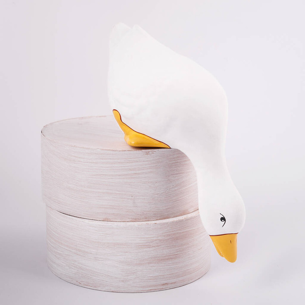 Ceramic duck stay on double stump and look down. Isolated white duck for garden - Valokuva, kuva