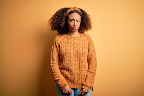 Giovane donna afro americana con i capelli afro indossa maglione casual su sfondo giallo scettico e nervoso, accigliato sconvolto a causa di problemi. Persona negativa
. - Foto, immagini