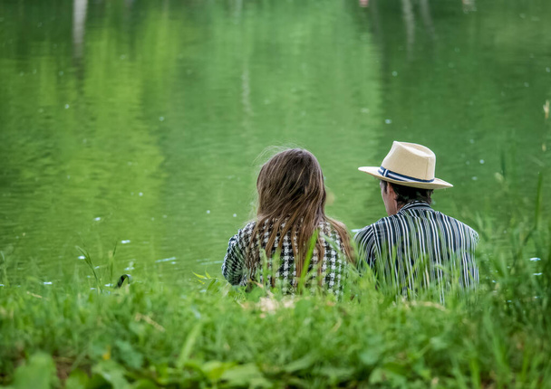 Couple relaxing on the edge of a lake in Youth Park, Bucharest. - Photo, Image