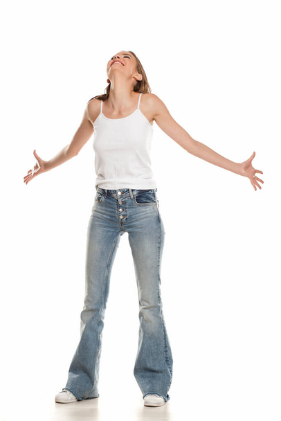 Happy young pretty woman posing in bell bottom jeans on white background - 写真・画像