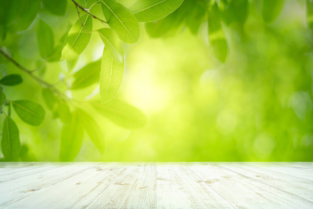 Fresh green leaves nature with bokeh on empty wooden table background for product display template and copy space using as background natural greenery landscape or wallpaper - Photo, Image