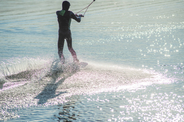 Ο wakeboarder κάνει κόλπα. Χαμηλή γωνία του ανθρώπου wakeboarding σε μια λίμνη. - Φωτογραφία, εικόνα