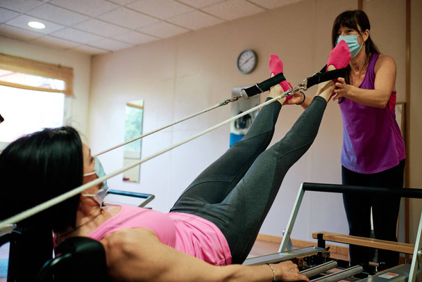 Egzersiz yapan bir grup olgun kadın, sosyal mesafeli Pilates ve Yoga yapıyor ve yüz maskesi takıyor. - Fotoğraf, Görsel