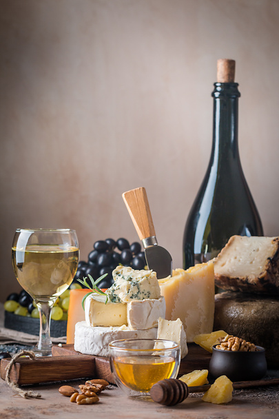 various types of cheese with honey, grapes and wine on rustic background - Photo, image