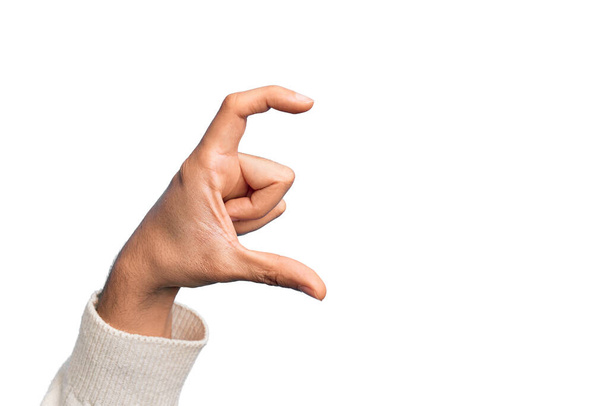 Hand of caucasian young man showing fingers over isolated white background picking and taking invisible thing, holding object with fingers showing space - Photo, Image