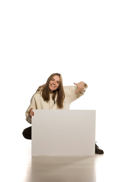 Jeune modèle en sweat à capuche montre un panneau publicitaire vide sur fond blanc
 - Photo, image