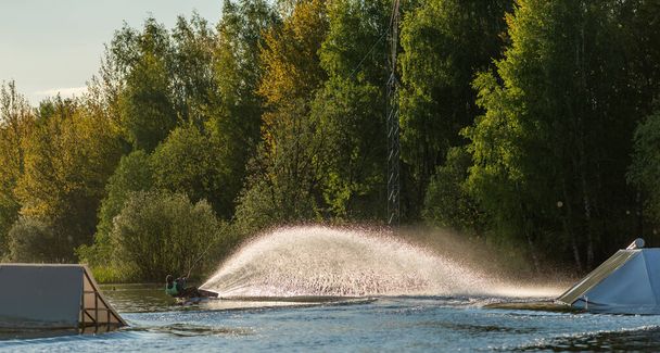 Wakeboarder making tricks. Low angle shot of man wakeboarding on a lake. - Photo, Image