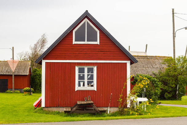 Mały czerwony piękny drzewny zadbany tradycyjny dom w Szwecji w szary deszczowy dzień - Zdjęcie, obraz