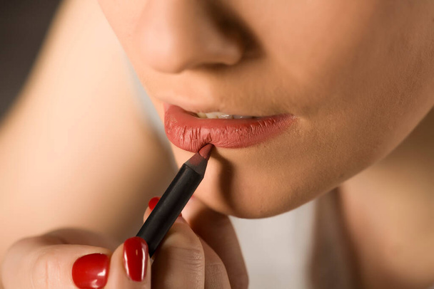 Jeune femme appliquant crayon à lèvres
  - Photo, image