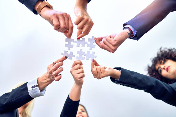 Группа бизнес-работников с руками, соединяющими кусочки головоломки в офисе
 - Фото, изображение