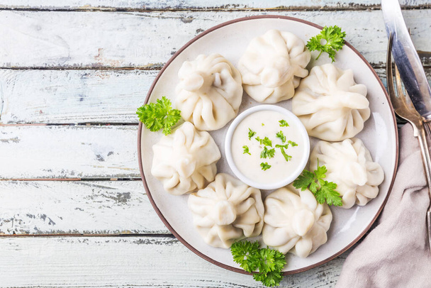 Georgian dumplings Khinkali with meat, greens and sauce on white plate, top view - 写真・画像