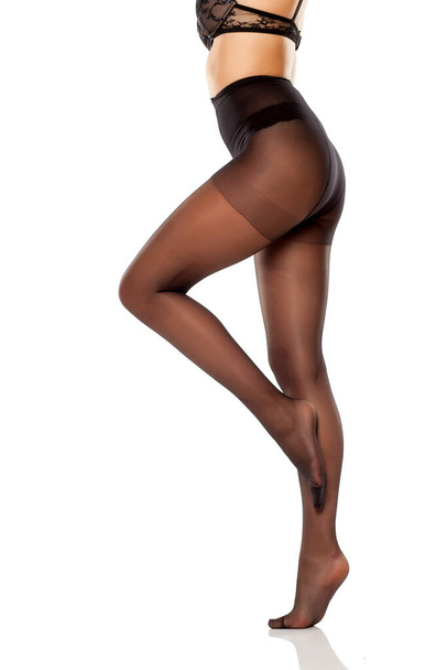belle gambe lunghe femminili e calze nere in nylon a vita alta su sfondo bianco
 - Foto, immagini