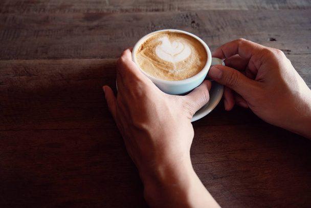 hands holding hot cup of coffee on rustic wooden table background - Φωτογραφία, εικόνα