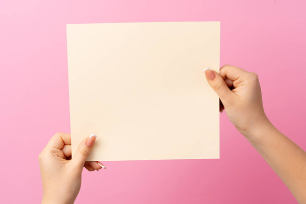 Woman hand showing blank business card on pink background. - 写真・画像