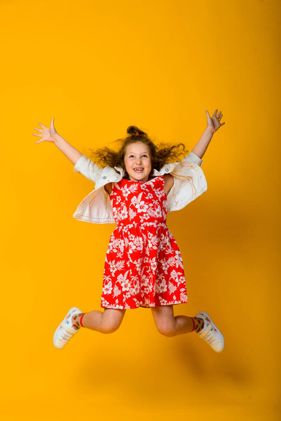 Happy carefree child emotions. Energetic joyful adorable little girl laughing at joke on yellow background in studio. - Фото, изображение