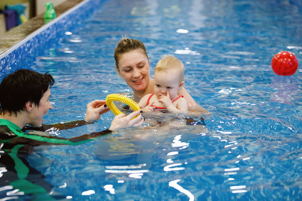 Mujer entrenador de niños y niños pequeños nadan y estudian en la piscina de agua azul
 - Foto, imagen