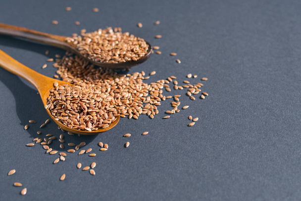 Dry flax seeds in wooden spoons on a dark surface - Foto, Imagem