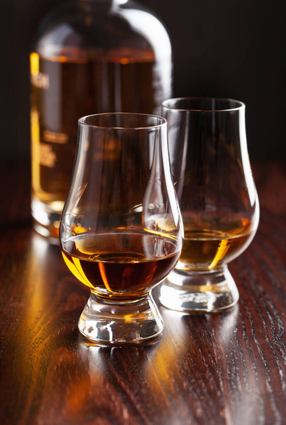 Fles en glas whiskybrandewijn op donkerbruine achtergrond - Foto, afbeelding